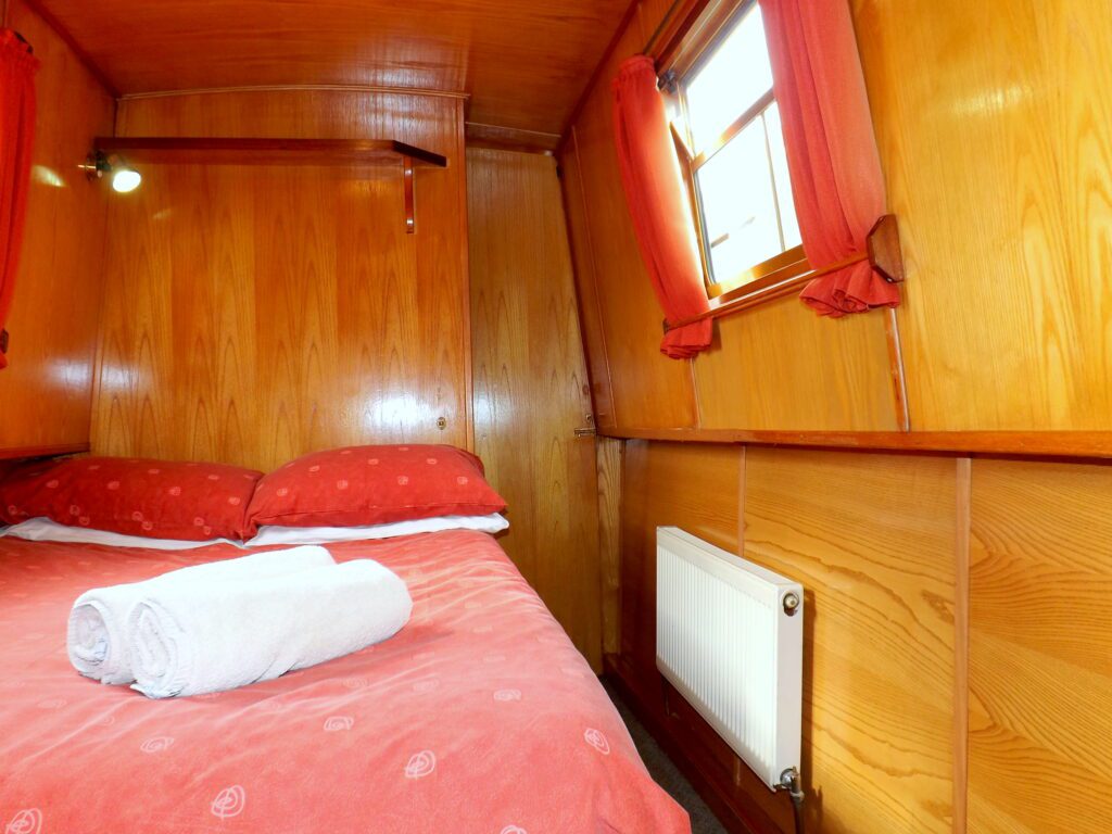 The forward double cabin on narrowboat Foxhunter with a comfortable fixed double bed and plentiful storage.