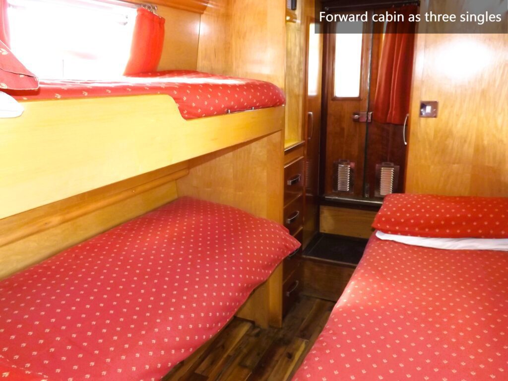 Forward cabin on WilyFox narrowboat with three single beds and wooden interior.