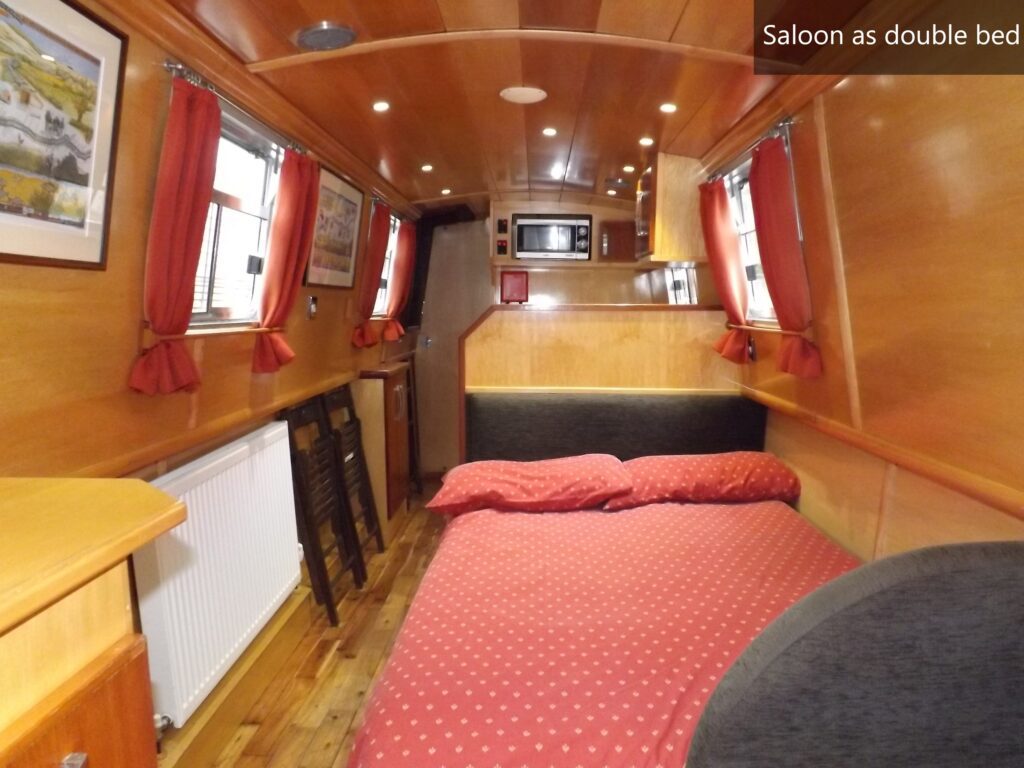 Saloon seating on WilyFox narrowboat converted into a single bed with red patterned mattress