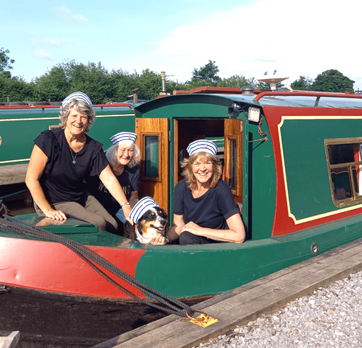 Three happy ladies and their dog in sailor hats onboard a Foxhangers narrowboat